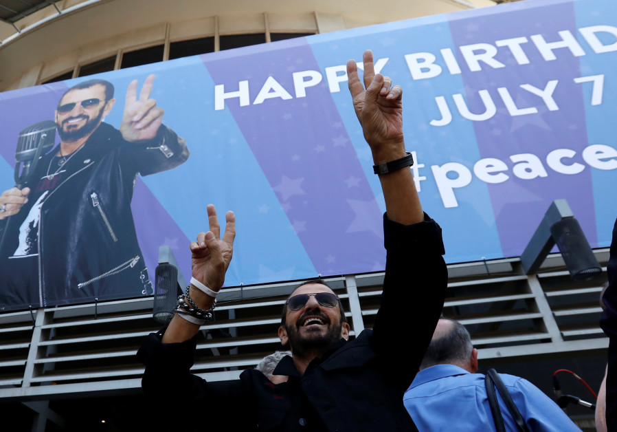 Musician Ringo Starr gestures at fans at a 'Peace & Love' event to celebrate Starr's 77th birthday i