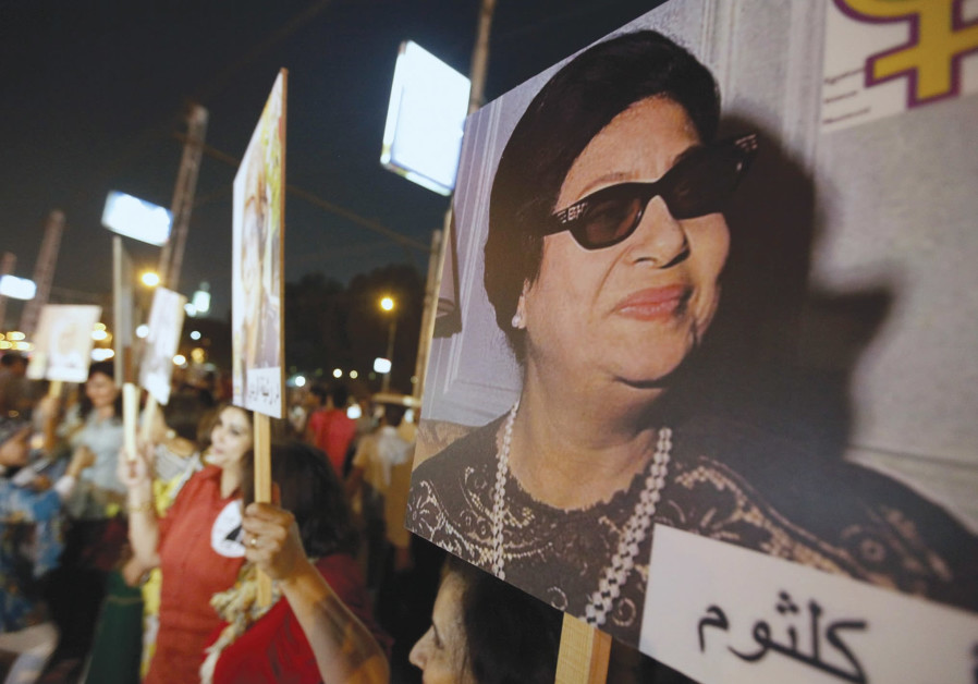 WOMEN CARRY photos of the late Egyptian singer Oum Kalthoum, who despite writing songs that included