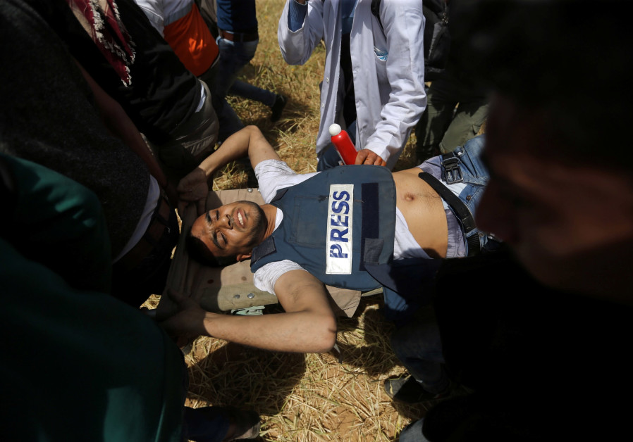Palestinians aid an injured journalist during protests in Gaza