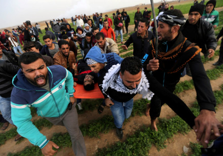 A wounded Palestinian is evacuated during anti-Trump protests that clashed with Israeli troops in Ga