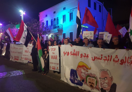 People protest the recent air strikes in Syria in front of the defunct US consulate in Haifa