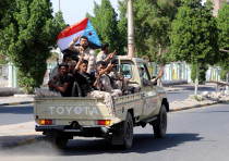Southern Yemeni separatist fighters flash the V sign as they ride on the back of a truck in Aden