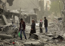PEOPLE WALK through debris in the center of Afrin, Syria, on March 24, 2018.