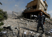 A Syrian firefighter stands among the rubble of the scientific research center targeted by coalition