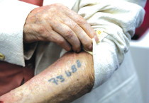 A Holocaust survivor shows his tattoo