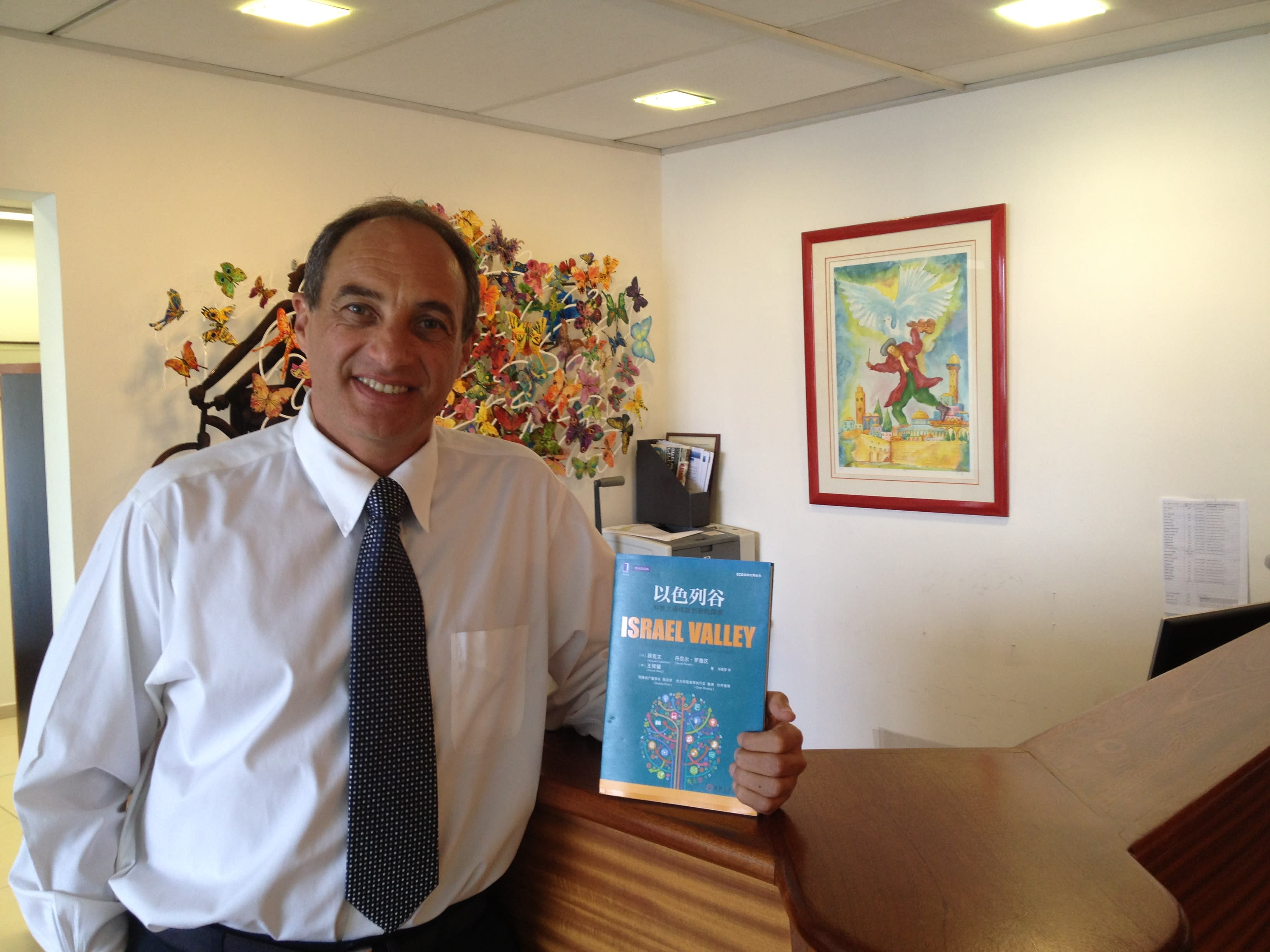 Israeli private equity investor Edouard Cukierman holds up a book he co-authored that was translated into Mandarin in 2014. Cukierman is focusing evermore on Chinese investment into Israel (Courtesy)