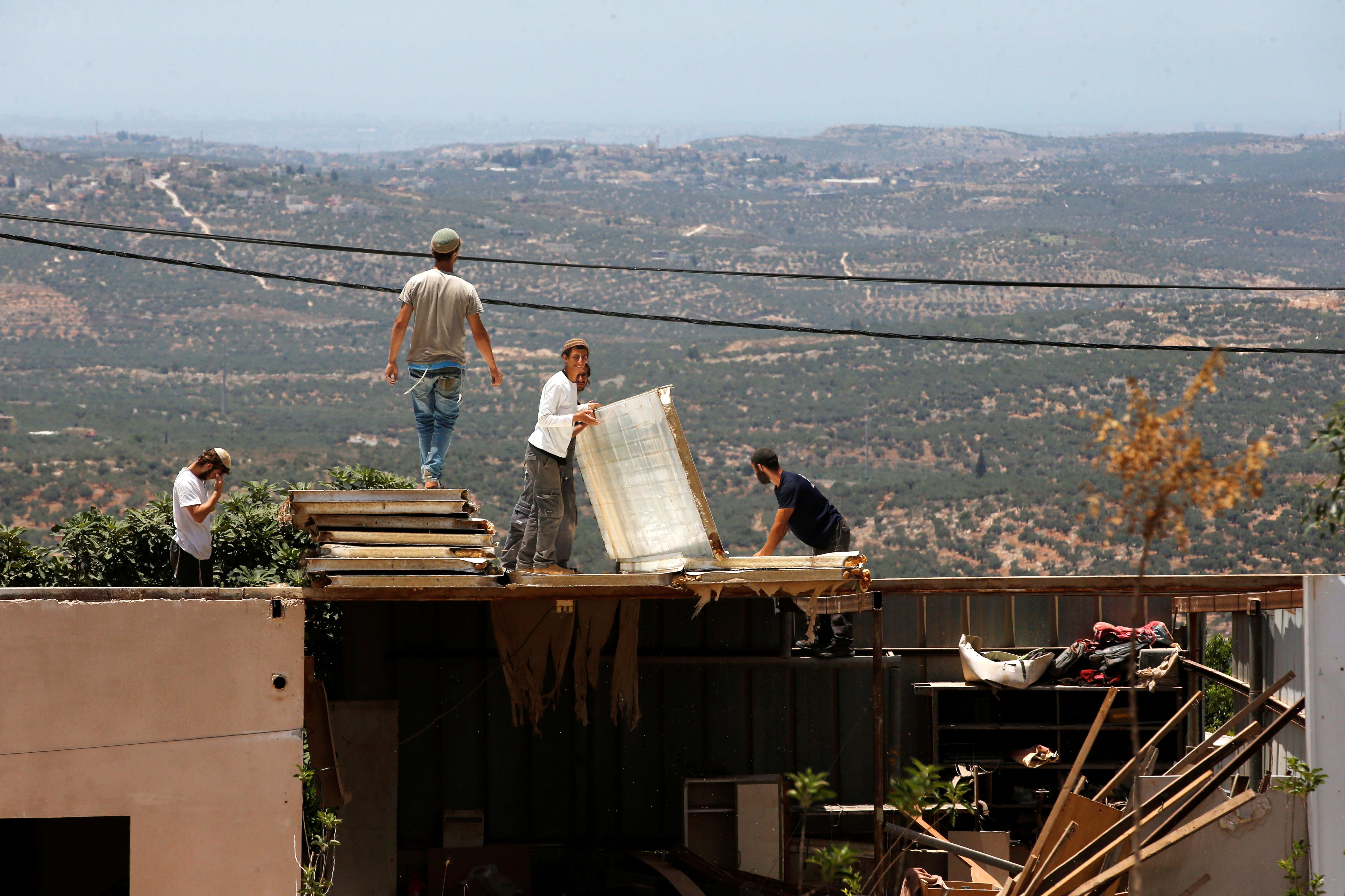 Jewish settlers dismantle parts of a structure during the eviction of buildings that an Israeli court deemed to have been built illegally in Tapuach West settlement, in the Israeli occupied West Bank, June 17, 2018.