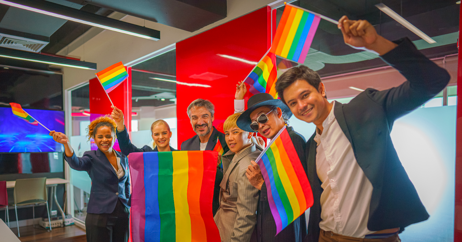 Office employees celebrating pride with flags (Credit: AdobeStock)