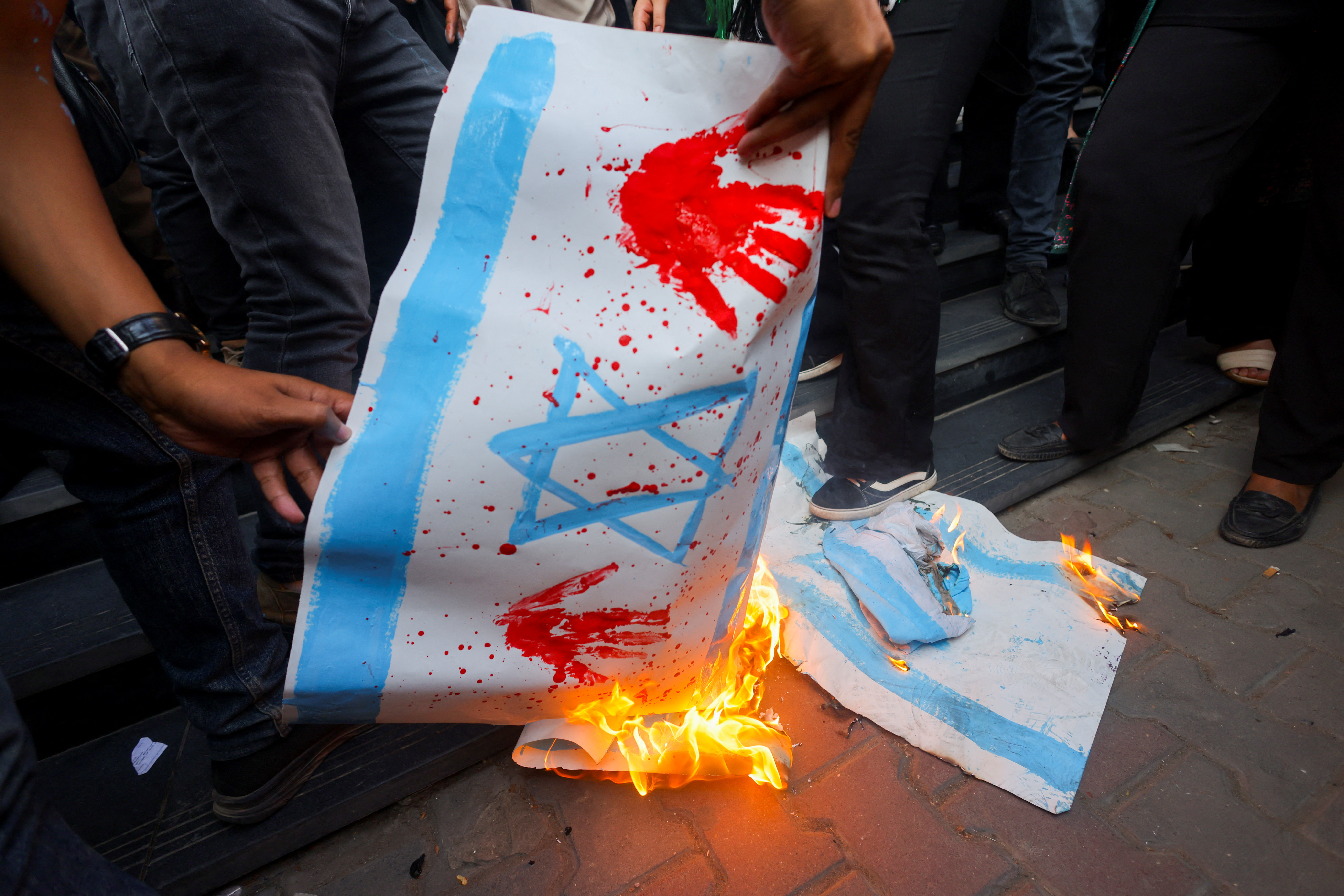 Demonstrators burn banners depicting the Israeli flag during a protest against Israel and the USA in support of Palestinians for those killed in a blast at Al-Ahli hospital in Gaza that Israeli and Palestinian officials blamed on each other, amid the ongoing conflict between Israel and Hamas, in Cairo, Egypt, October 18, 2023. REUTERS/Amr Abdallah Dalsh