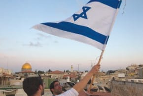 A JEWISH man waves a flag with the Temple Mount in the background.