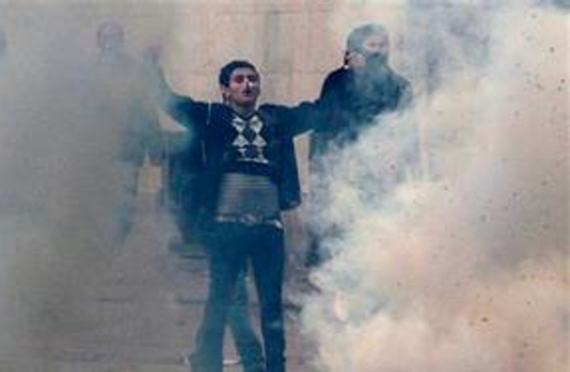 Tunisian rioter stands in tear gas clouds 311 AP (photo credit: AP)