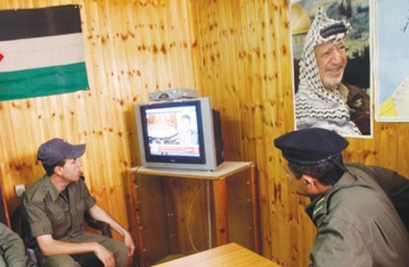 Palestinian security officers watch TV 390 (photo credit: Abed Omar Qusini/Reuters)