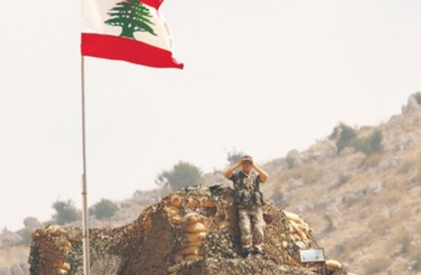 Lebanese soldier peers at Israel along border 370 (photo credit: Ali Hashisho/Reuters)