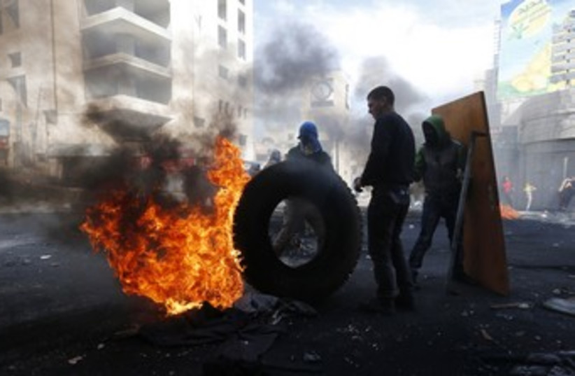 Palestinian protesters next to burning tyre in Hebron 370 (photo credit: reuters)