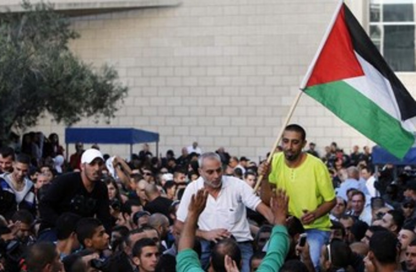 Israeli Arab man raises Palestinian flag 370 (photo credit: REUTERS/Nir Elias)