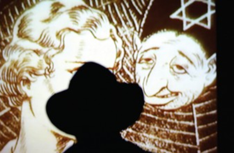 A MAN looks at a Nazi propaganda poster at Yad Vashem. (photo credit: REUTERS)