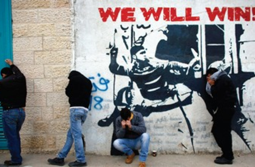 PALESTINIANS STAND next to a wall in Bethlehem. (photo credit: REUTERS)
