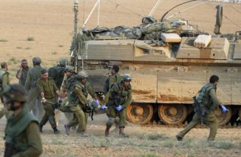 IDF soldiers carry a comrade on a stretcher, who was wounded during an operation in Gaza, outside northern Gaza July 20, 2014. (photo credit: REUTERS)