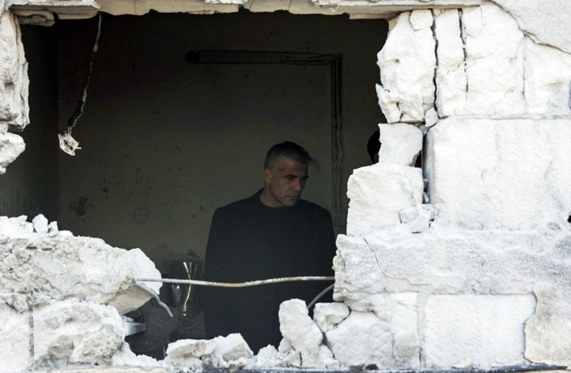 Israeli Finance Minister Yair Lapid stands in a house damaged by a rocket, fired by Palestinian militants, that landed in the southern town of Sderot (photo credit: REUTERS)