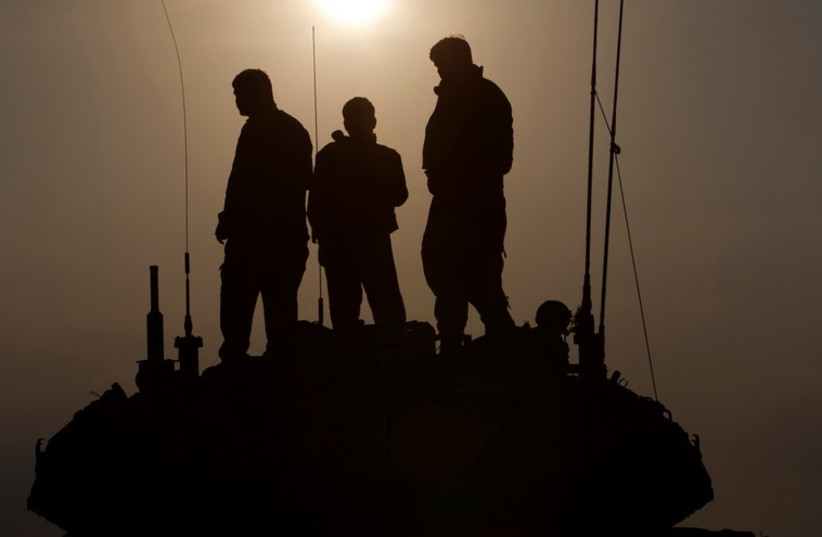 IDF soldiers stand atop a tank near the border with Gaza. [File] (photo credit: REUTERS)