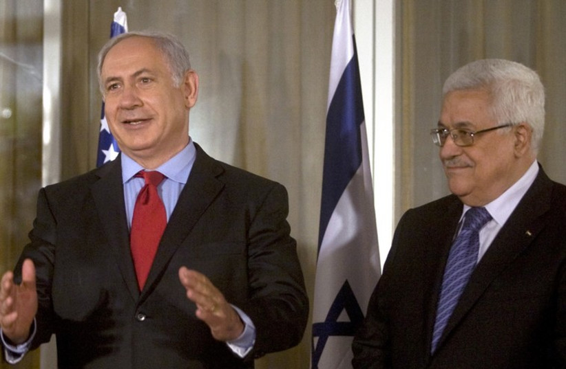 Prime Minister Benjamin Netanyahu (L) gestures as Palestinian Authority President Mahmoud Abbas looks on (photo credit: REUTERS)