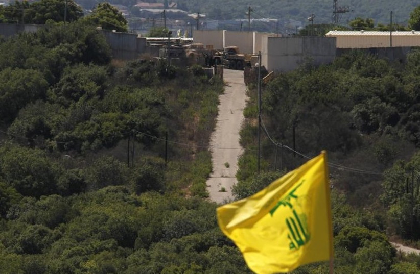 Israeli soldiers and trucks are seen from southern Lebanon, as a Hezbollah flag flutters. (photo credit: REUTERS)