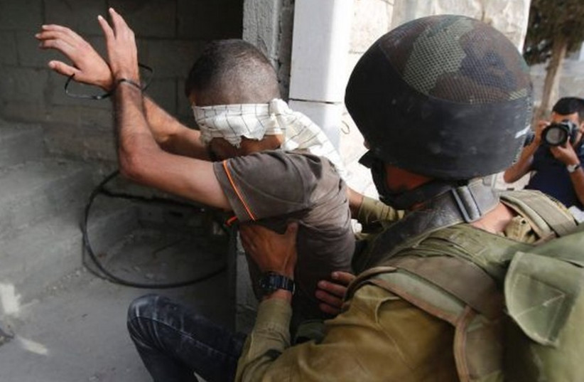 An IDF soldier detains a Palestinian near Hebron. (photo credit: REUTERS)