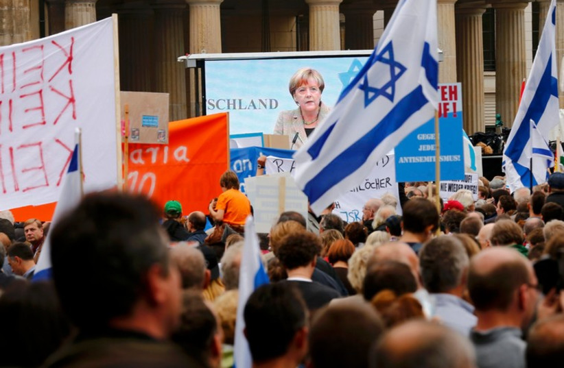 German Chancellor Angela Merkel (C) appears on a large screen as she makes an address during an anti-Semitism in Berlin. (photo credit: REUTERS)
