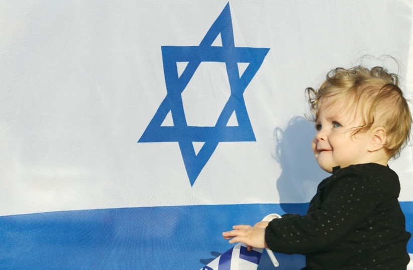 A baby sits in front of an Israeli flag (photo credit: MARC ISRAEL SELLEM/THE JERUSALEM POST)
