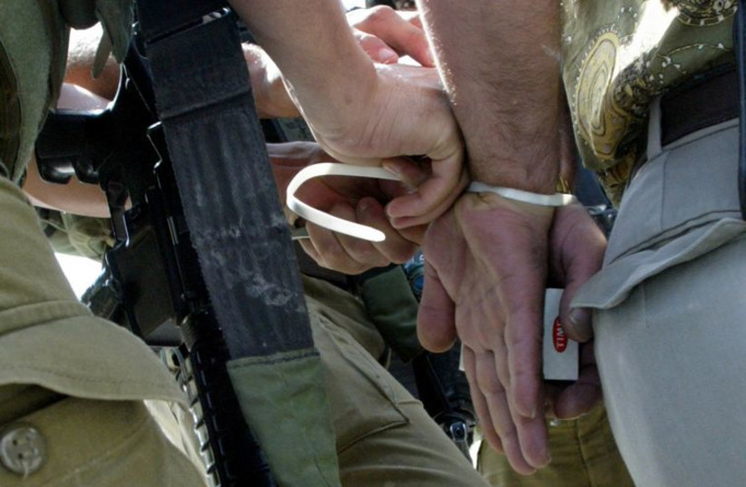 IDF soldier handcuffs a man (photo credit: REUTERS)