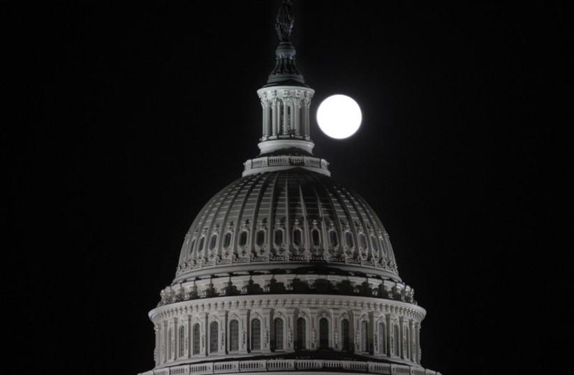 The full moon rises behind the US Capitol Dome in Washington  (photo credit: REUTERS)