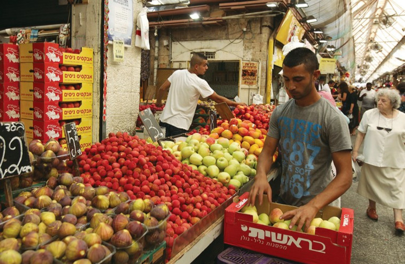 A vegetable vendor restocks his supply in Jerusalem’s Mahaneh Yehuda market. (photo credit: MARC ISRAEL SELLEM/THE JERUSALEM POST)