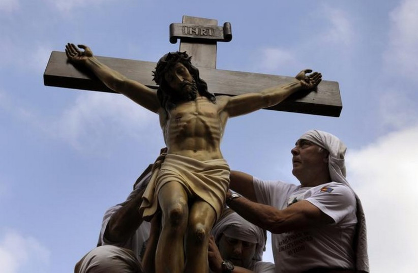 Penitents place a statue of Jesus Christ on top of a float during the Palm Sunday procession of the "Estudiantes" brotherhood in Oviedo, northern Spain (photo credit: REUTERS)