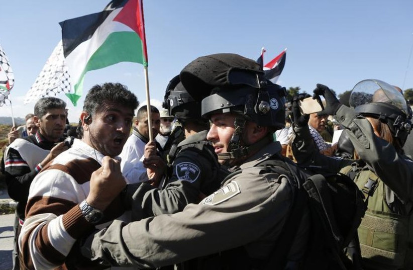 A Palestinian protester confronts a Border Police officer during an anti-settlement protest in the West Bank (photo credit: REUTERS)