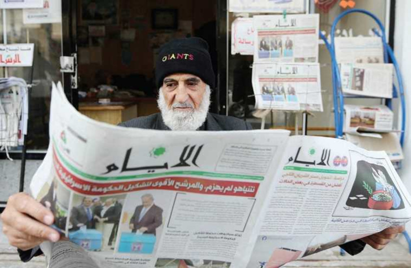 A Gaza man reads a newspaper, featuring the Israeli election on its front page, in Khan Younis, March 18. (photo credit: IBRAHEEM ABU MUSTAFA / REUTERS)