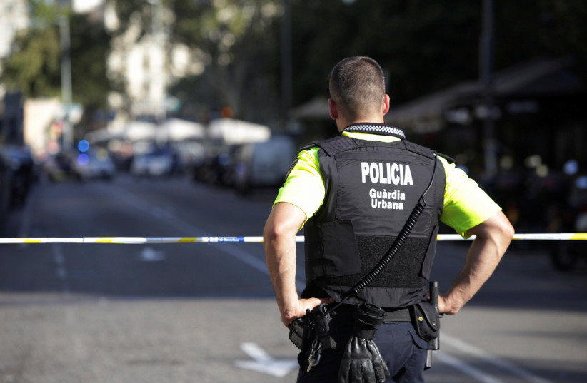 A Spanish police officer looks over a street in Barcelona after a van ramming attack there killed 13, August 18, 2017. (photo credit: REUTERS/STRINGER)