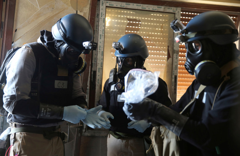 A United Nations (U.N.) chemical weapons expert, wearing a gas mask, holds a plastic bag containing samples from one of the sites of an alleged chemical weapons attack in the Ain Tarma neighbourhood of Damascus, Syria August 29, 2013. (photo credit: REUTERS/MOHAMED ABDULLAH)
