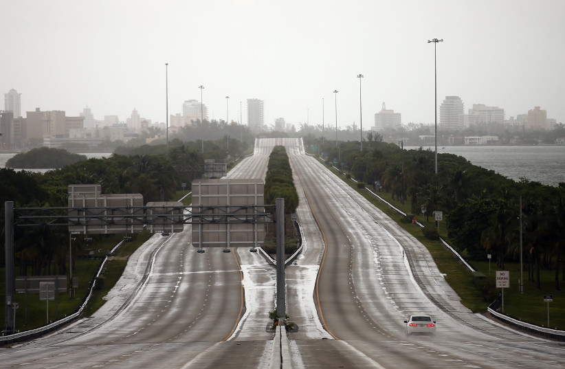A car drives along an empty highway in Miami before the arrival of Hurricane Irma in south Florida (photo credit: CARLOS BARRIA / REUTERS)