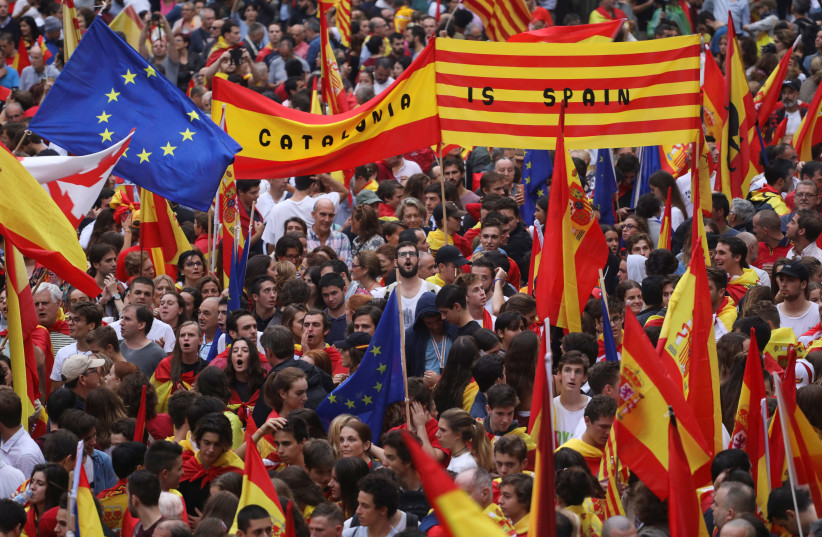 People wave Spanish, Catalan (known as Senyera) and European Union flags during a demonstration in favor of a unified Spain a day before the banned October 1 independence referendum, in Barcelona, Spain, September 30, 2017. (photo credit: REUTERS/SUSANA VERA)