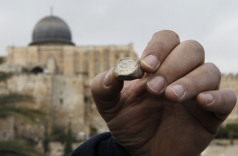 Israel Antiquities Authority (IAA) archaeologist Eli Shukron shows an ancient seal, at an archaeological site known as the City of David in Jerusalem December 25, 2011. (photo credit: REUTERS/Ronen Zvulun)