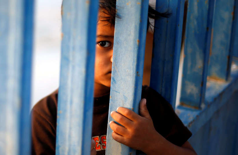 A Palestinian boy standing by a gate looks on as he waits for the return of his relatives after performing the annual Haj pilgrimage in Mecca, at Rafah border crossing in the southern Gaza Strip, September 13, 2017 (photo credit: REUTERS/MOHAMMED SALEM)