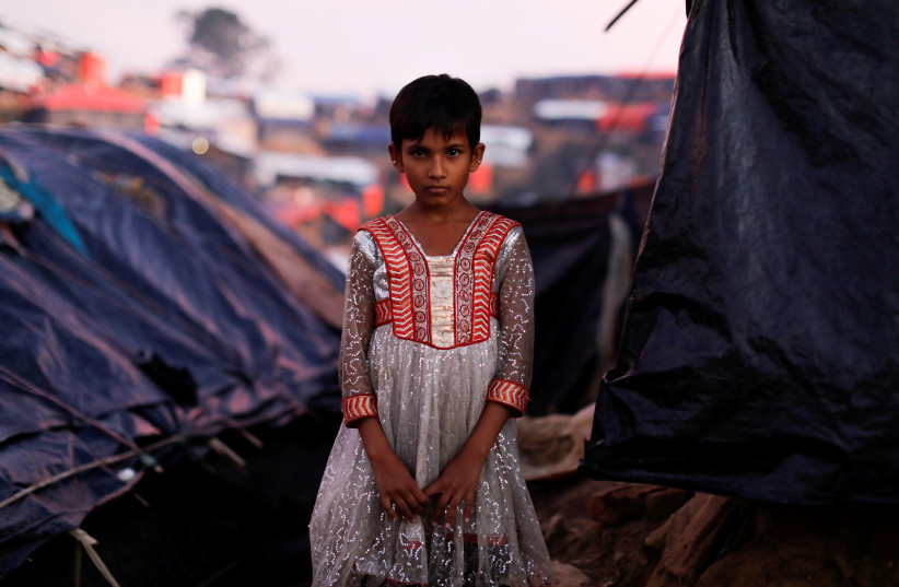 Mujan Begum, a 8-year-old Rohingya refugee, who arrived one month ago with her family poses outside her makeshift tent at a refugee camp near Cox's Bazar, Bangladesh October 11, 2017. (photo credit: REUTERS)