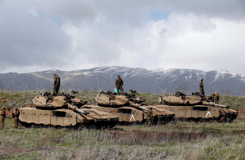 Israeli soldiers stand atop tanks overlooking the border between Israel and Syria (photo credit: RONEN ZVULUN / REUTERS)