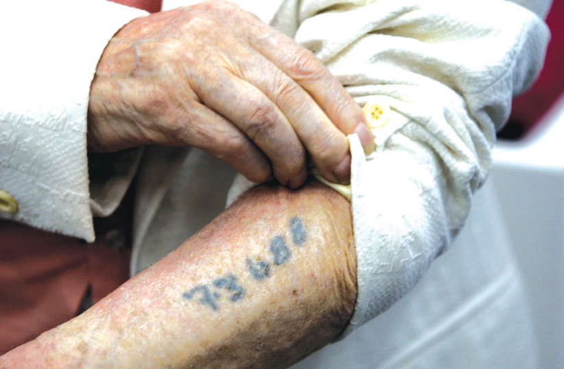 A Holocaust survivor shows the number that was tattooed on his arm in a Nazi concentration camp during the Holocaust (photo credit: BAZ RATNER/REUTERS)