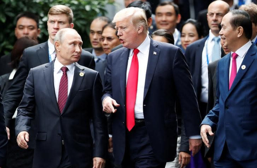 US President Donald Trump and Russia's President Vladimir Putin talk as Vietnam's President Tran Dai Quang (R) looks on, during the family photo session at the APEC Summit in Danang, Vietnam November 11, 2017 (photo credit: REUTERS/JORGE SILVA)