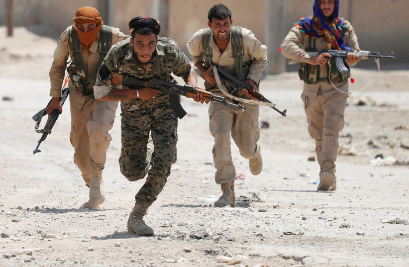 Kurdish fighters from the People's Protection Units (YPG) run across a street in Raqqa, Syria  (photo credit: REUTERS/GORAN TOMASEVIC/FILE PHOTO)