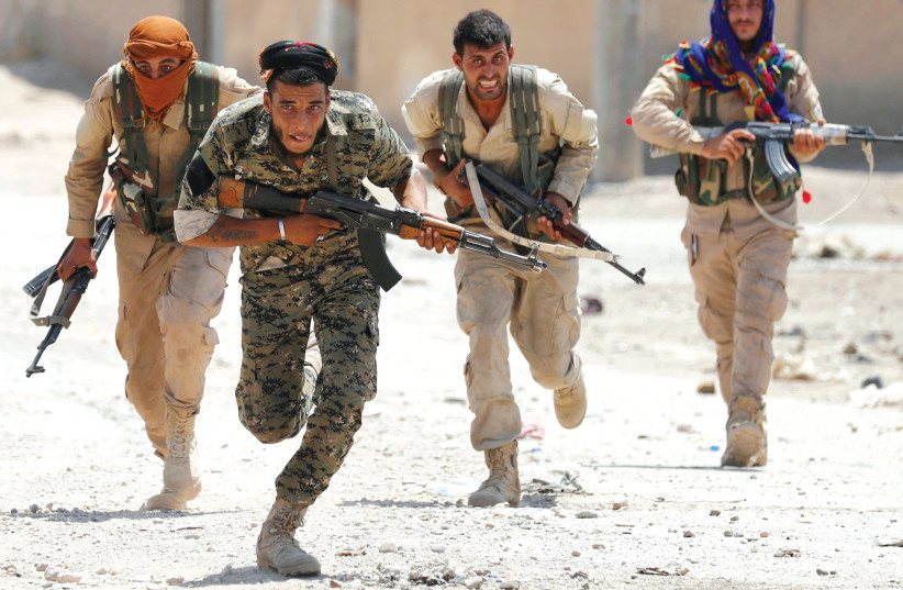KURDISH FIGHTERS from the People’s Protection Units (YPG) run across a street in Raqqa, Syria in July. (photo credit: GORAN TOMASEVIC/REUTERS)