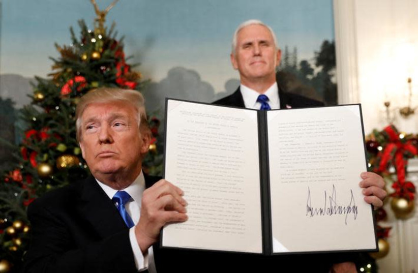U.S. Vice President Mike Pence stands behind as U.S. President Donald Trump holds up the proclamation he signed that the United States recognizes Jerusalem as the capital of Israel and will move its embassy there, during an address from the White House in Washington, U.S., December 6, 2017 (photo credit: KEVIN LAMARQUE/REUTERS)