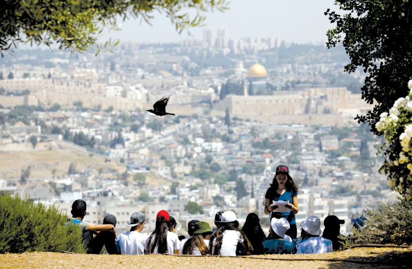 A CROW flies past as schoolchildren gather at a look-out point on the Armon Hanatziv Promenade in Jerusalem (photo credit: AMIR COHEN/REUTERS)