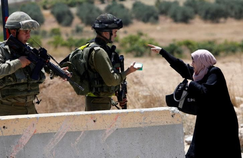 A Palestinian woman argues with Israeli army soldiers as she is searched at a checkpoint during clashes in the West Bank Al-Fawwar refugee camp, south of Hebron (photo credit: REUTERS/MUSSA QAWASMA)